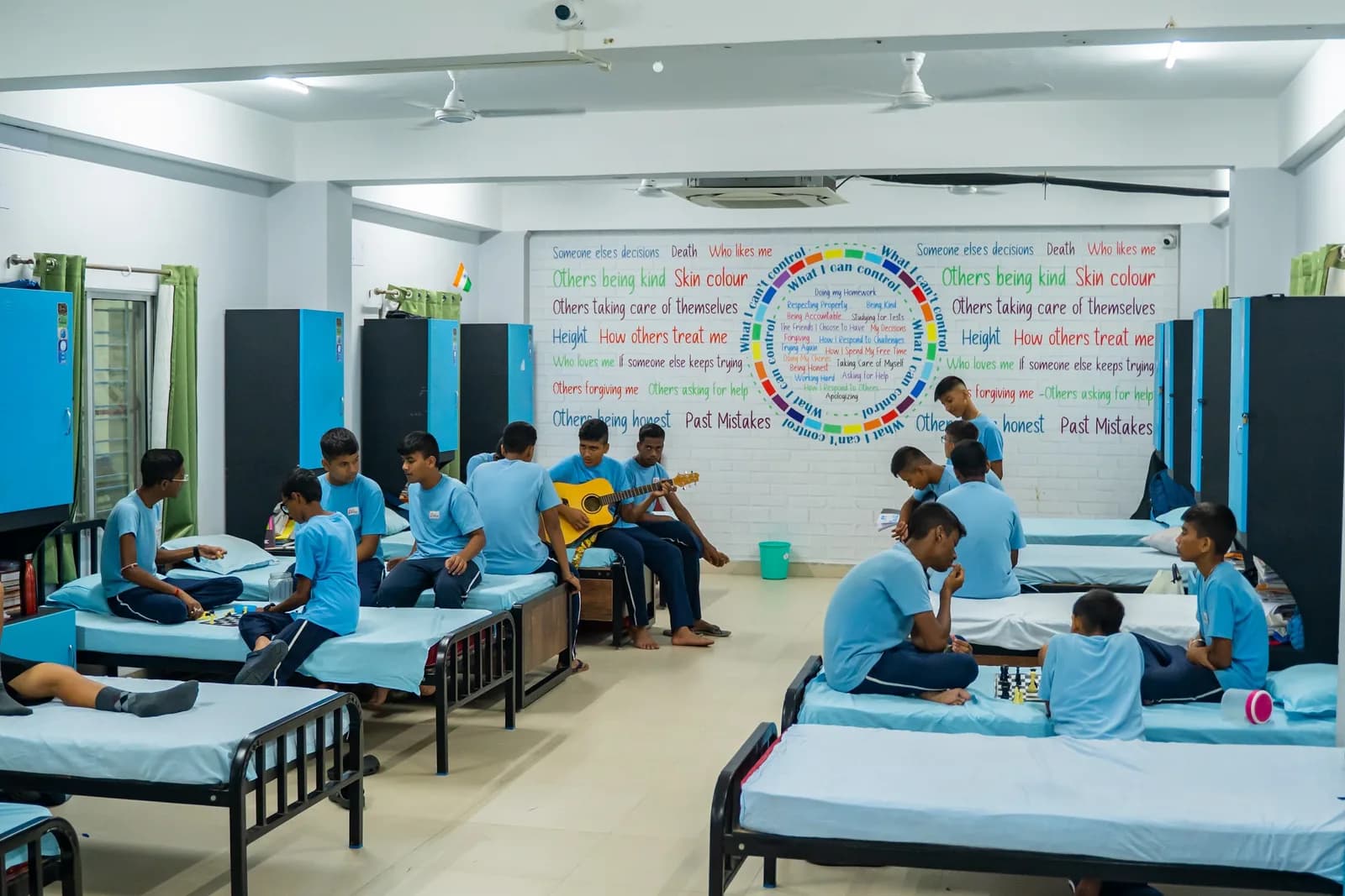 Boarders playing games and music together in a hostel dormitory at Sri Sri Academy